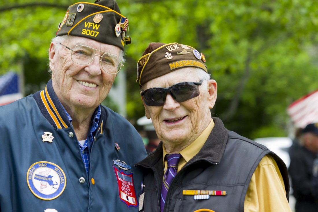  Two older veterans stand side-by-side at a Memorial Day service
